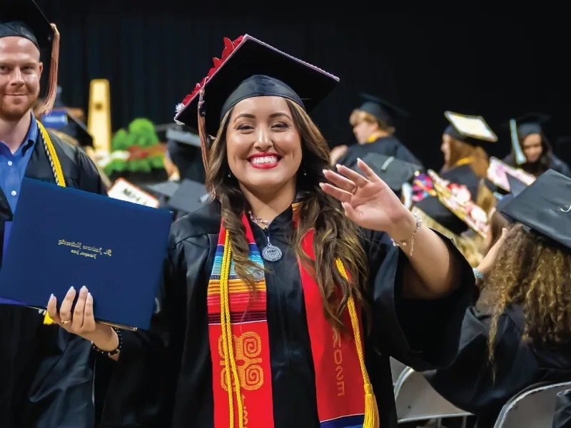 Graduate waving during commencement ceremony.